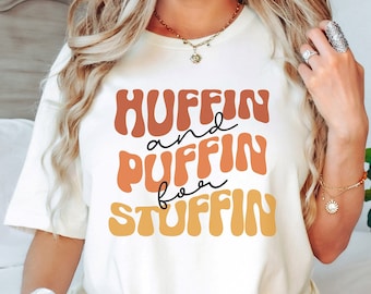 May include: White t-shirt with a retro-style graphic that says "Huffin and Puffin for Stuffin".