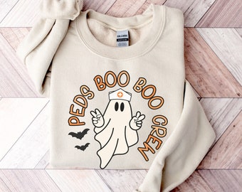 May include: A beige sweatshirt with a graphic of a ghost wearing a nurse's hat and the text "Peds Boo Boo Crew".