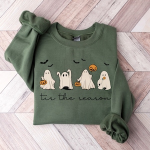 May include: Green sweatshirt with a white graphic of five ghosts holding pumpkins and a flower. The text "Tis the season" is printed below the ghosts.