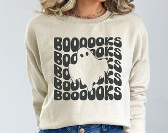 May include: A cream-colored sweatshirt with a black graphic of a ghost and the text "BOO-OOKS" repeated in a retro font.