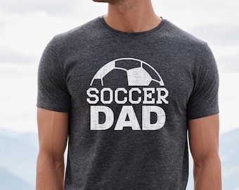 May include: A dark gray t-shirt with a white soccer ball graphic and the text "SOCCER DAD" in white.