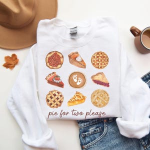 May include: White sweatshirt with a graphic of nine different pie slices and the text "pie for two please".