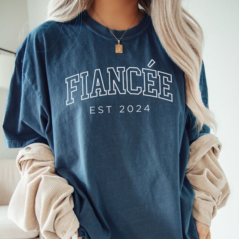 Puede incluir: Una camiseta azul oscuro con el texto "FIANC&Eacute;E EST 2024" en blanco.