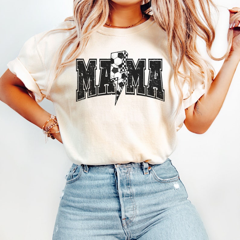 May include: A white t-shirt with a black and white checkered lightning bolt graphic and the word "MAMA" in black block letters.