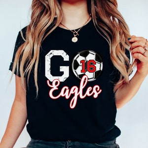 May include: Black t-shirt with a white distressed "GO" and "Eagles" in white script. A football with the number 16 in red is between the words.