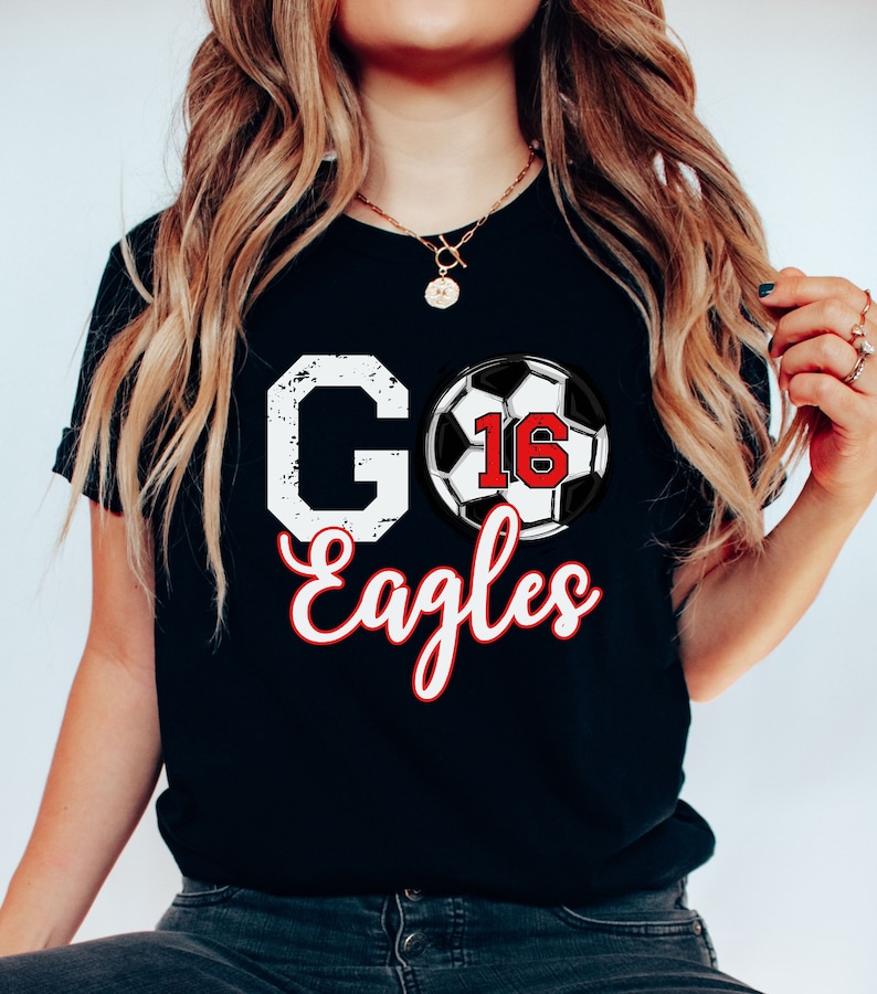 May include: Black t-shirt with a white distressed "GO" and "Eagles" in white script. A football with the number 16 in red is between the words.