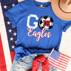May include: Blue t-shirt with a white "GO" and "Eagles" text and a football with the number 16 on it.