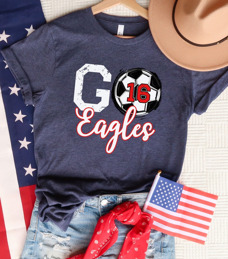 May include: A navy blue t-shirt with a white graphic of a football with the number 16 and the words "Go Eagles" in red and white.