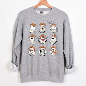 May include: A gray sweatshirt with a design of nine cartoon ghosts wearing cowboy hats and various accessories, including a lasso, a guitar, and a gun.