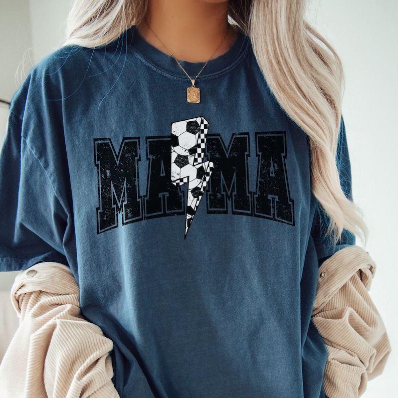 May include: A blue t-shirt with a black and white checkered lightning bolt graphic and the word "MAMA" in black letters.