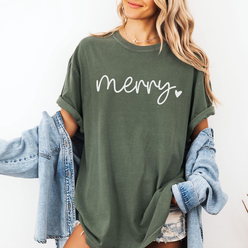 May include: A green t-shirt with the word "merry" written in white cursive with a small white heart next to it.