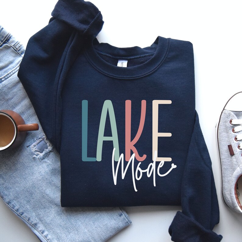 May include: A navy blue sweatshirt with the text "LAKE Mode" in colorful letters. The letters are in shades of teal, green, pink, and beige.