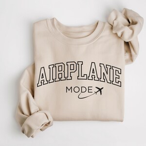 May include: A beige sweatshirt with the text "AIRPLANE MODE" in black lettering with a small airplane graphic.
