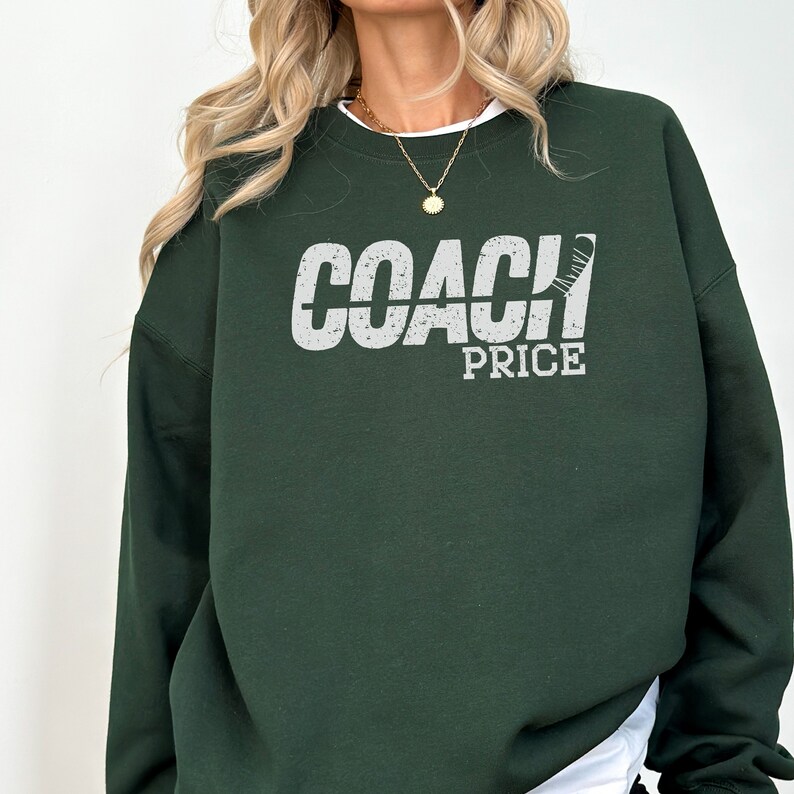 May include: A dark green sweatshirt with the text "COACH PRICE" in white with a hockey stick graphic.