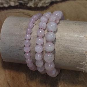 Peut inclure: Trois bracelets en quartz rose rose sur une surface en bois. Les bracelets sont faits de perles rondes et sont enfilés sur un élastique.