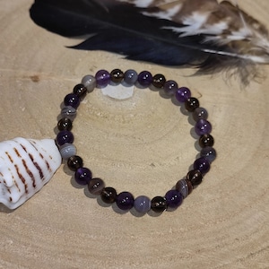 Peut inclure: Un bracelet composé de perles de pierres précieuses brunes et violettes. Les perles sont rondes et ont une finition lisse et polie.