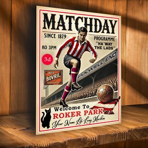 Può includere: Un poster in stile vintage per una partita di calcio a Roker Park. Il poster presenta un calciatore con una maglia a strisce rosse e bianche che calcia un pallone, con il testo "Matchday" e "Benvenuti a Roker Park" in grandi caratteri grassetto.