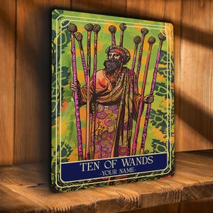 Puede incluir: Impresión de carta de tarot con los Diez de Bastos. La ilustración representa una figura vestida con una túnica que sostiene diez varas. El fondo es verde con detalles florales. La carta tiene una pancarta azul con el texto "TEN OF WANDS -YOUR NAME-".