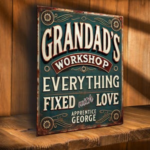Op de afbeelding: Een vintage metalen bord met een blauwe achtergrond en gouden accenten. Het bord staat er "Grandad's Workshop Everything Fixed with Love Apprentice George" op.