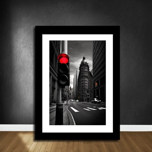 May include: A black and white photograph of a city street with a red traffic light in the foreground. The street is empty except for a few cars in the distance. The buildings in the background are tall and imposing.