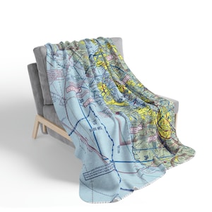 May include: A blue and white throw blanket with a map of San Francisco printed on it. The map shows the city's airspace with various flight paths and altitudes. The text "SAN FRANCISCO TERMINAL AREA CHART" is printed in the bottom right corner.