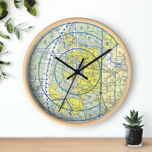 May include: A round wooden clock with a map of Washington, D.C. and surrounding areas. The clock face features a yellow and blue map with black clock hands.