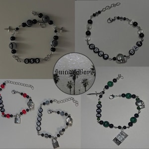 May include: A collection of beaded bracelets with various designs. Some bracelets feature black and white beads, others have red and black beads, and some include green beads. Several bracelets have the text "G59", "GREY DAY", or "RUBY".