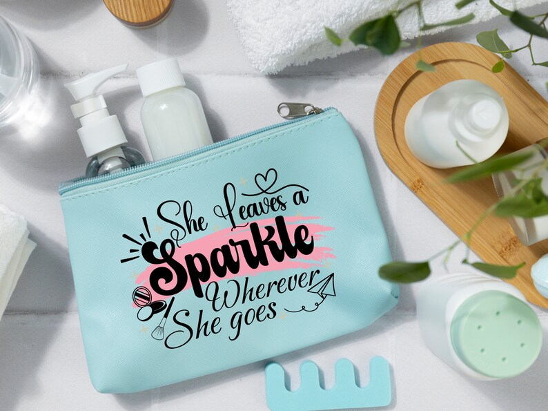 May include: A light blue zippered makeup bag with a pink and white design. The bag has the text "She leaves a sparkle wherever she goes" printed on it.