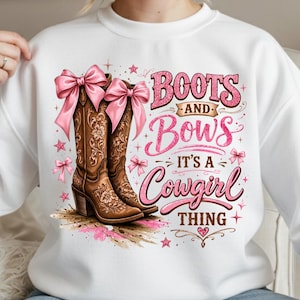 Op de afbeelding: Witte sweatshirt met een ontwerp van bruine cowboylaarzen met roze strikken en de tekst "Boots and Bows It's a Cowgirl Thing". Het ontwerp bevat roze sterren en accenten.