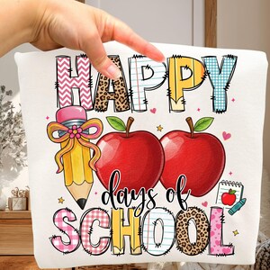 May include: White pillow with a colorful "Happy days of SCHOOL" design. Features a pencil, two red apples, and stars. The letters have various patterns, including leopard print and plaid.
