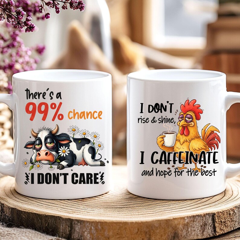 May include: Two white ceramic mugs with humorous graphics. One mug features a cow with the text "There's a 99% chance I DON'T CARE." The other mug has a rooster with the text "I DON'T rise & shine, I CAFFEINATE and hope for the best."