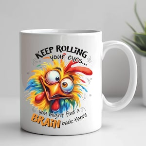 May include: White ceramic mug featuring a cartoon chicken with a colorful design. The chicken has large, expressive eyes and a red comb. Text on the mug reads "KEEP ROLLING your eyes... you might find a BRAIN back there."