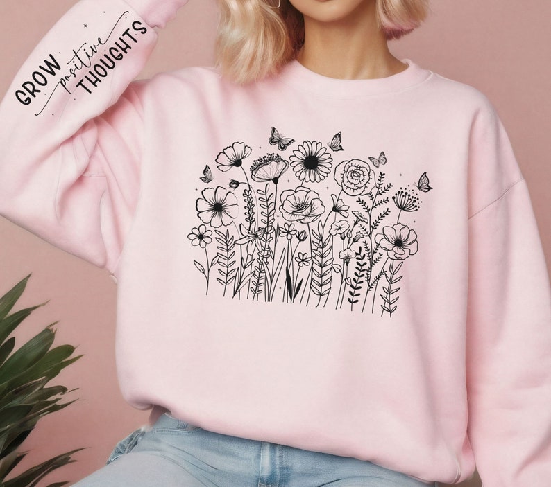 Może przedstawiać: R&oacute;żowa bluza z czarnym rysunkiem kwiat&oacute;w i motyli. Na rękawie znajduje się napis "GROW positive THOUGHTS".