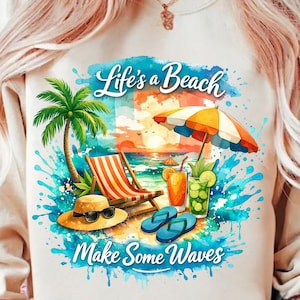 May include: Cream-colored sweatshirt with a beach-themed graphic. The design features a beach scene with text that reads "Life's a Beach, Make Some Waves." Includes a palm tree, beach chair, umbrella, drinks, and sunglasses.
