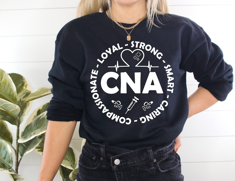 May include: Black sweatshirt with a white circle graphic that says "CNA" with a heart, EKG line, syringe, and pills around it. The text around the circle says "Caring - Smart - Strong - Loyal - Compassionate -  Advocate".