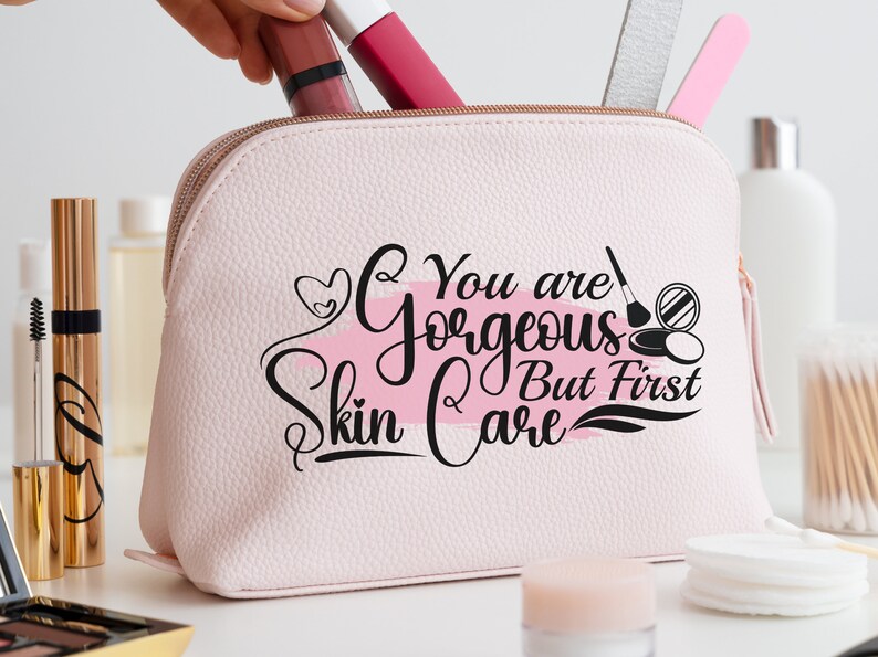 May include: Pink cosmetic bag with a white and pink brushstroke design and the text "You are gorgeous but first skin care".