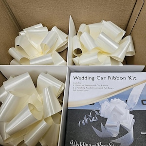 May include: A wedding car ribbon kit containing three large, ivory-coloured pull bows. The kit includes 9 metres of waterproof car ribbon and matching bows. The box has the text "Wedding Car Ribbon Kit" and the website "Wedding and PartyStore.com".