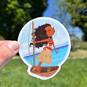 May include: A circular sticker featuring a cartoon illustration of a person with long dark wavy hair, wearing a red and beige patterned outfit, standing on a small wooden boat with a mast, set against a bright blue ocean and sky background.