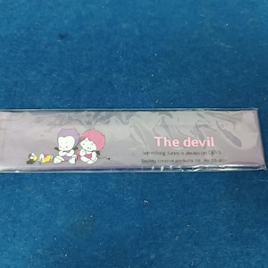 Puede incluir: Una regla de plástico morada con una imagen de dibujos animados de dos diablos. La regla tiene el texto "The devil" y "Something funny is always on DEVIL" impreso en ella. El texto "Soundy creative products ltd. No: 25-4121" también está impreso en la regla.