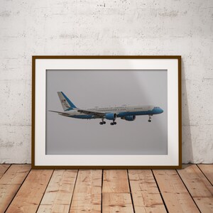 May include: A white and blue airplane with the words "United States of America" on the side, framed in a brown frame.