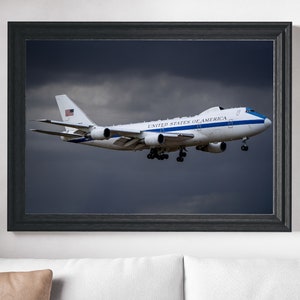 May include: A white Boeing 747 airplane with blue accents and the text "UNITED STATES OF AMERICA" on the side, flying in a cloudy sky.