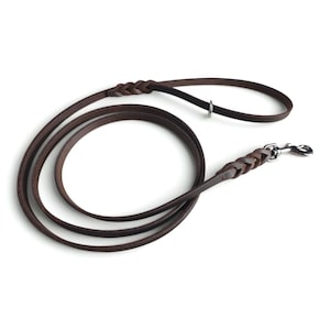May include: A dark brown leather dog lead featuring braided detailing at the handle and near the silver-toned metal swivel snap hook. The lead is coiled in a circular shape and includes a small metal ring attached to the handle section.