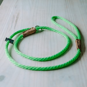 May include: A bright green rope dog leash with brown leather accents and a silver metal clip.