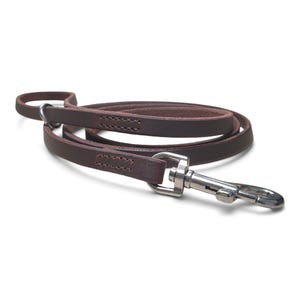 May include: A dark brown leather lead featuring a silver-toned metal swivel snap hook at one end and a loop handle at the other. The strap is constructed with reinforced stitching near the hardware, providing a secure connection for the metal clasp.