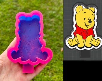 May include: A pink silicone mold shaped like Winnie the Pooh. The mold is designed to create a 3D Winnie the Pooh figure. The mold is shown in a hand.