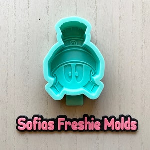 May include: A light blue silicone mold of a cartoon character wearing a helmet. The mold is for making fondant or other edible decorations. The mold is labeled "Sofias Freshie Molds".