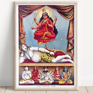 Puede incluir: Una impresión hindú enmarcada y colorida que presenta una deidad vestida de rojo con múltiples brazos, flotando sobre una figura reclinada. Debajo, se representan varias figuras sentadas. La obra de arte está ambientada sobre un fondo azul con cortinas ornamentadas.