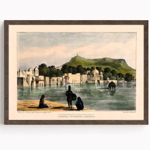 May include: Framed print of a vintage landscape scene featuring a body of water with buildings and a mountain in the background. The print has a brown frame and includes figures in the foreground. The text at the bottom reads "Part of the Bathing Place in the Sacred Lake of PUSHKUR-POOSHKUR AJMEER."