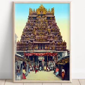Pode incluir: Uma impressão emoldurada de um templo indiano colorido e ornamentado. O templo é uma estrutura de vários níveis com entalhes intrincados e detalhes dourados. Pessoas estão reunidas em frente ao templo, com um céu azul claro.