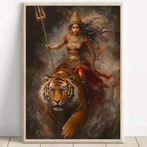 Puede incluir: Una impresión artística enmarcada representa a una mujer con atuendo dorado y rojo montada en un tigre. Sostiene un tridente dorado. La obra de arte tiene un estilo pictórico con un fondo oscuro y atmosférico. El tigre es naranja y negro.